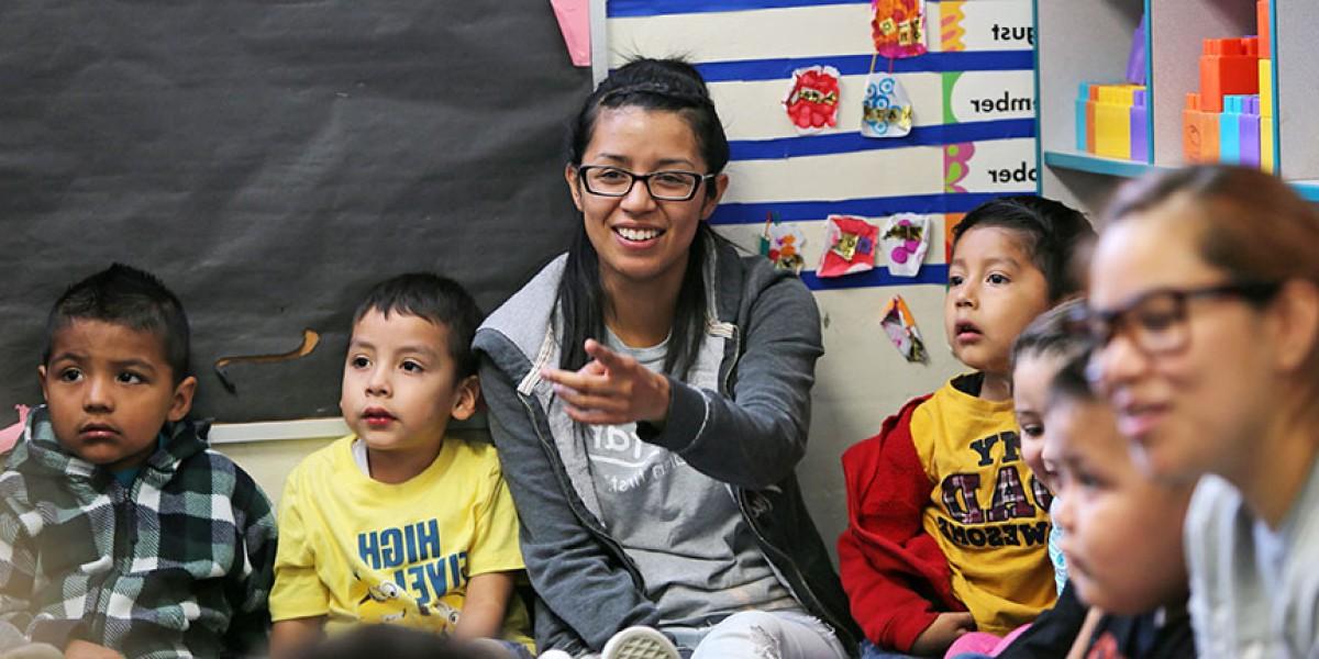 A student sitting on a floor surrounded by children.