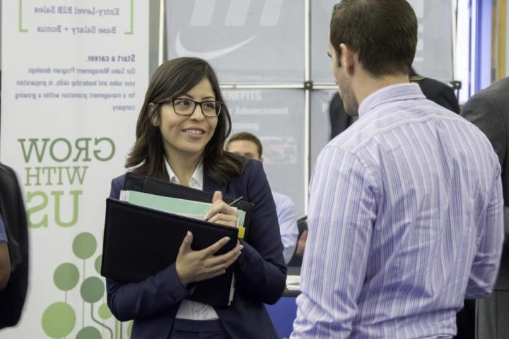 Student in professional clothes talks to an employer at the career fair